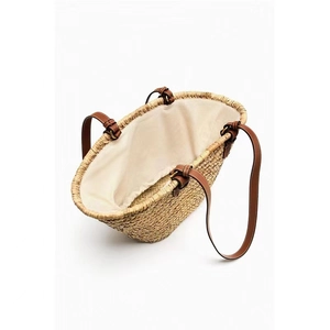 Minimalist straw tote bag with brown leather straps and spacious interior for beach vacation