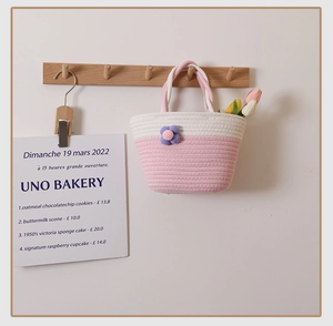 Detail of pink and white woven cotton handbag with a plush flower and braided handle