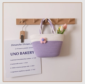 Close-up of handmade woven mini tote bag featuring dual-color knit and plush flower detail