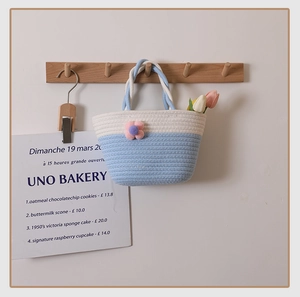 Detail of hand-woven cotton bag featuring pink floral decor and dual blue handles