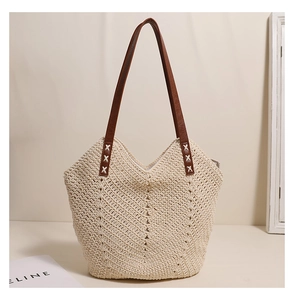 Detail of V-shaped hollow woven straw tote bag with brown faux leather handle and white stitching