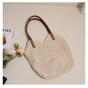 Detail of cream woven tote with brown faux leather handles and white X-shaped stitching