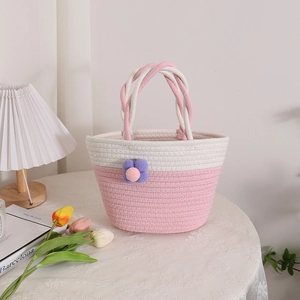 Handmade woven cotton rope bag with pink floral decoration and soft pom-poms handle