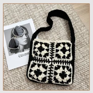 Detail of a handmade black and white granny square crochet tote bag with woven straps