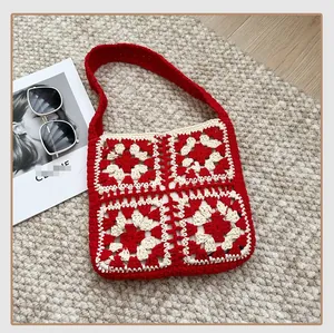 Flat lay of red and beige granny square crochet shoulder bag on a woven rug