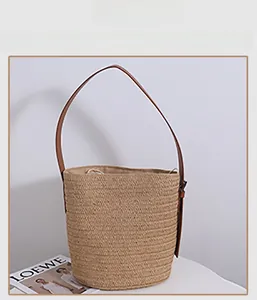 Detail of straw bucket bag with brown leather strap and secure drawstring lining closure