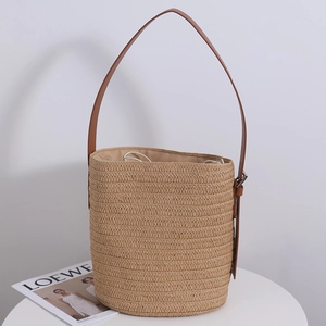Handwoven straw bucket bag with adjustable brown leather shoulder strap and drawstring lining