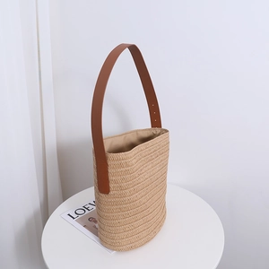 Minimalist straw bucket shoulder bag with brown leather strap for summer beach vacations