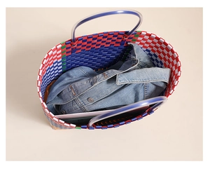 Deep view of large colorful woven plastic basket bag holding denim jacket and books