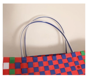 Close-up of multicolor woven tote bag featuring transparent PVC tube handles and red rivet detail