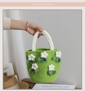 Close-up of handmade green knit camellia handbag with white 3D floral crochet details