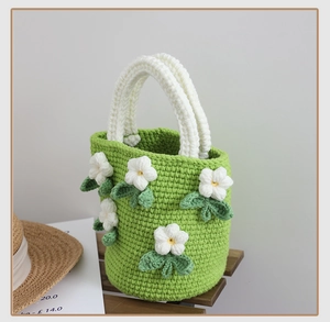 Macro shot of green crochet bucket bag showing 3D white camellia flowers and yarn texture