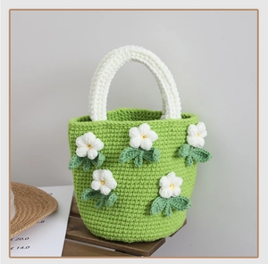 Close-up of green crochet handbag with white camellia flowers and woven texture