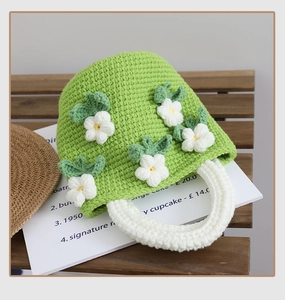 Detail of handmade crochet camellia handbag showing white floral 3D texture and green knit