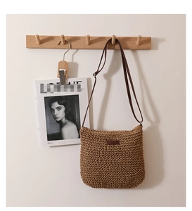 Detail of cross-body woven straw bag with fine texture and slim brown strap