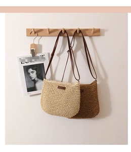 Detail of minimalist straw woven crossbody bag hanging on a wooden rack with leather straps