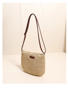 Detail of hand-woven straw crossbody bag featuring fine texture and brown leather strap