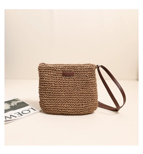 Detailed close-up of brown straw shoulder bag featuring textured woven patterns and leather patch