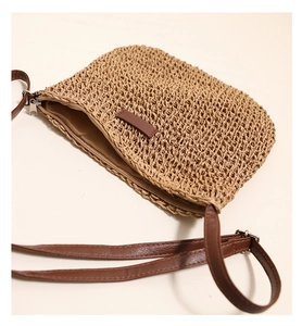 Detailed view of handmade woven straw crossbody bag with brown leather strap and zipper closure