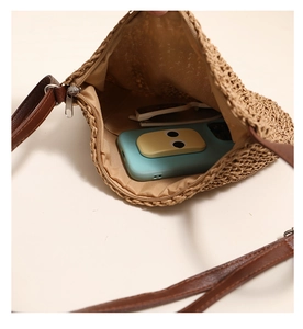 Interior detail of a straw crossbody bag showing space for a smartphone and sunglasses