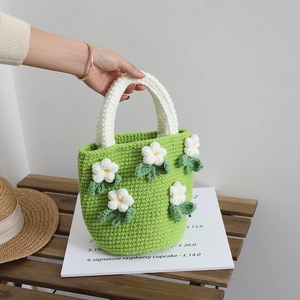 Handmade green crochet bucket bag featuring 3D white camellia flowers and woven handles
