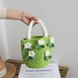 Handmade green crochet camellia bucket bag with white knit handles and floral details