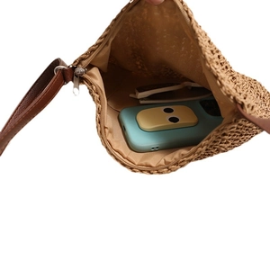 Crossbody woven straw bag with zipper and lining, showing inner space for phone and glasses