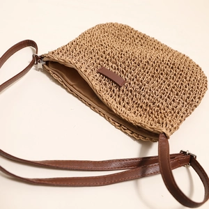 Handmade woven straw crossbody bag with brown leather strap for beach vacations