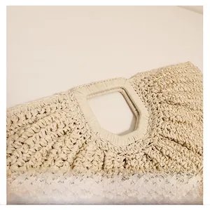 Close-up of the geometric handle and woven texture on a beige straw handbag