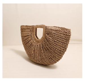 Detailed close-up of woven straw handbag showing natural texture and half-moon design