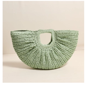 Detailed close-up of light green half-moon straw bag with unique radial pleated texture