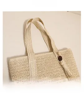 Detailed close-up of woven straw texture with tassel and wooden bead charms on beige tote