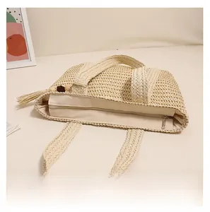 Detailed close-up of smooth zipper closure and woven handle on the beige straw beach bag