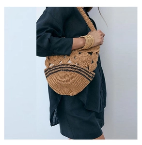 Detailed close-up of handmade woven straw bag with floral crochet pattern and black stripes