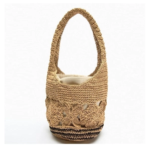 Detail of hand-woven straw shoulder bag featuring hollow flower patterns and drawstring liner