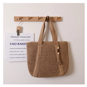 Detail of woven straw tote bag texture with decorative wooden bead tassel accent
