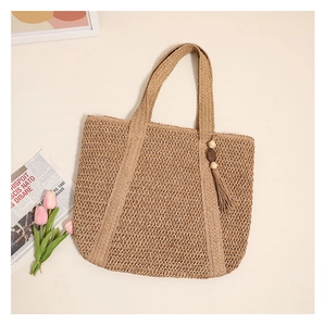 Detail of hand-woven straw tote with natural fiber texture and decorative tassel charm