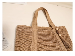 Close-up of woven straw tote bag featuring bohemian fringe and wooden bead charms