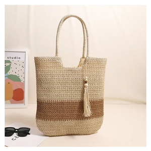 Detail der gewebten Strohtasche mit zweifarbigen Streifen und Holzperlen-Quastenverzierung