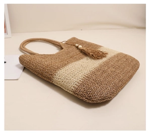 Detailansicht der zweifarbigen Strohtasche mit gewebten Texturen und Quasten