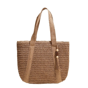 Handwoven straw tote bag in natural brown with bohemian tassel for beach vacations
