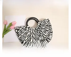 Detailed texture of semi-circular woven straw bag with black round handles for summer