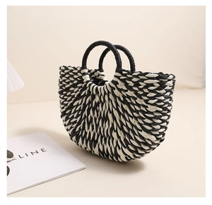 Close-up of semi-circle woven straw bag with black and white contrast and round handles