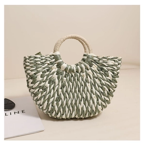 Close-up of sage green and beige woven straw handbag with a unique half-moon shape
