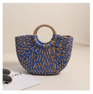 Detail of blue and natural semi-circle woven straw handbag with ring handle for beach