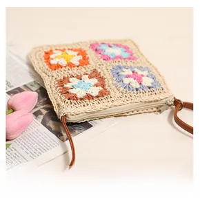 Detail of crochet straw bag showing colorful floral patterns and smooth metal zipper