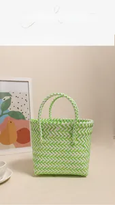 Detail of hand-woven plastic beach tote with green and white plaid pattern and dual handles