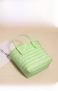 Detailed 45-degree angle view of green and white woven plastic beach tote bag