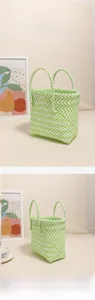 Detail of green and white woven plastic basket bag showing pattern and top handles