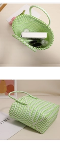 Detail of green and white woven plastic beach tote showing interior capacity and books